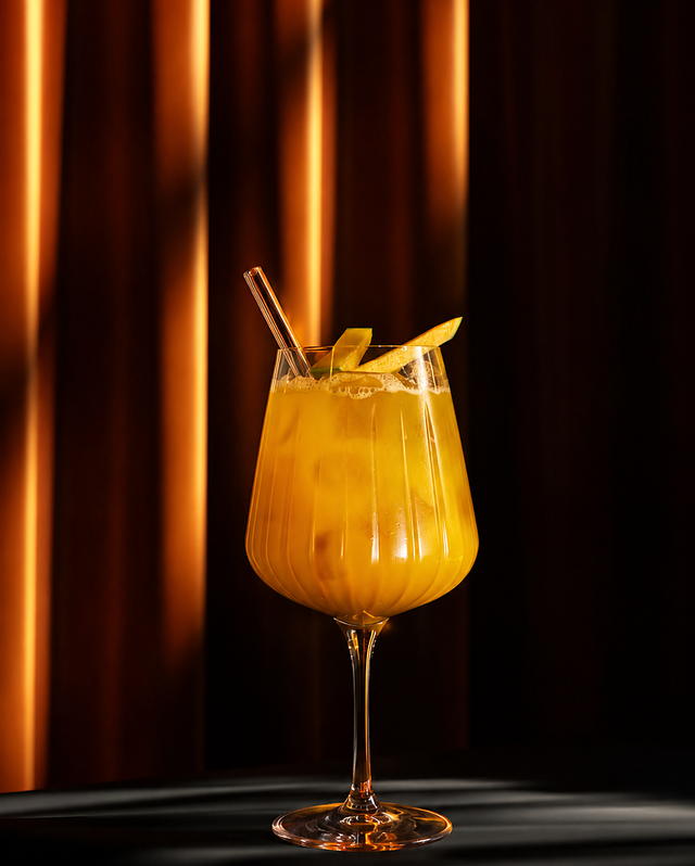 Mango spritz ve stopkové sklenici s plátky čerstvého manga