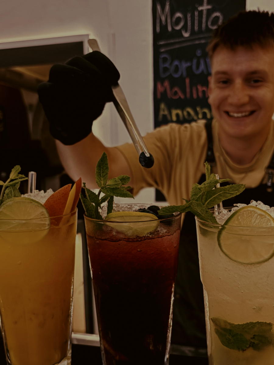 Barman v BAR&BARu dokončuje tři drinky s ovocem a mátou