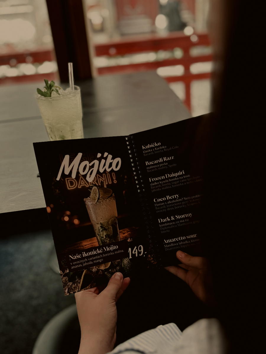 Host drží nápojový lístek BAR&BAR, na stole stojí mojito